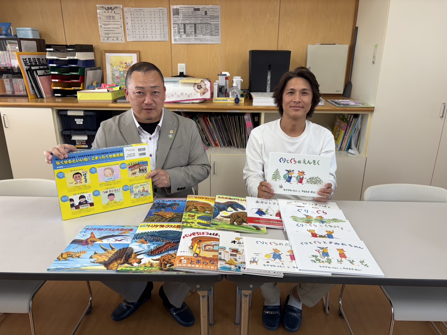 絵本を手にしたお二人と、テーブルに並べられた絵本